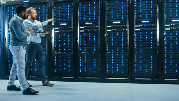 Two Data Center Professionals reviewing server infrastructure while walking through an active data center facility